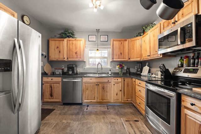 kitchen featuring dark countertops, stainless steel appliances, and a sink