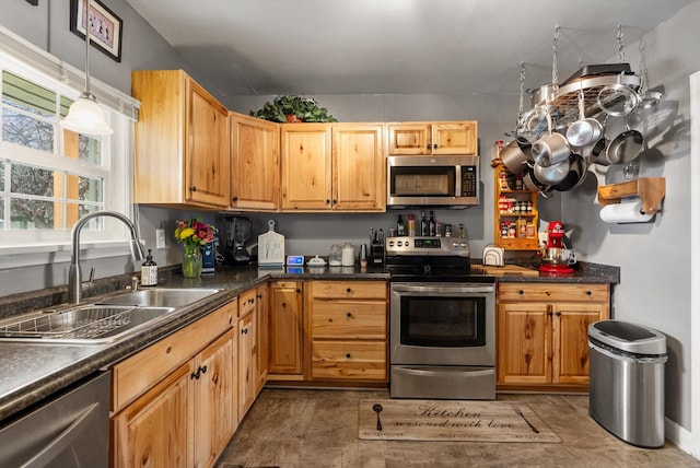 kitchen with decorative light fixtures, dark countertops, stainless steel appliances, and a sink