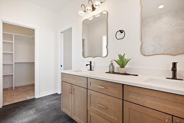 bathroom with a spacious closet, an inviting chandelier, a sink, and double vanity