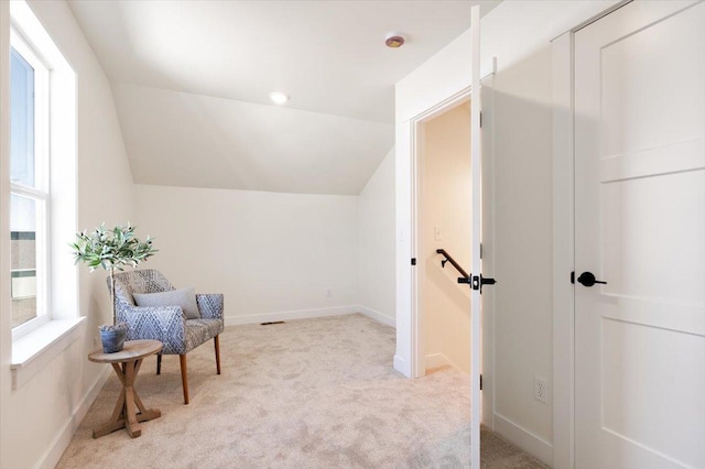 sitting room with light colored carpet, lofted ceiling, and baseboards