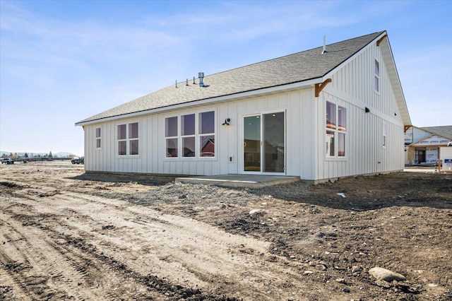 rear view of property with board and batten siding and a shingled roof