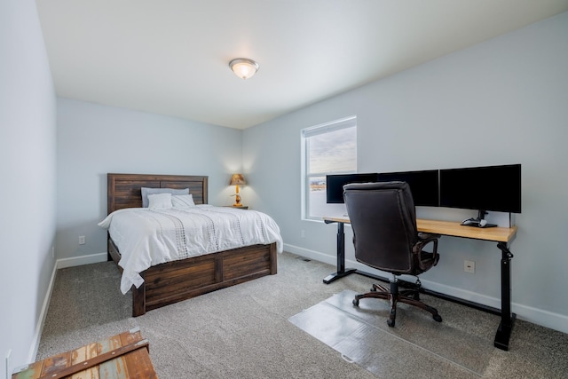carpeted bedroom with baseboards and a desk