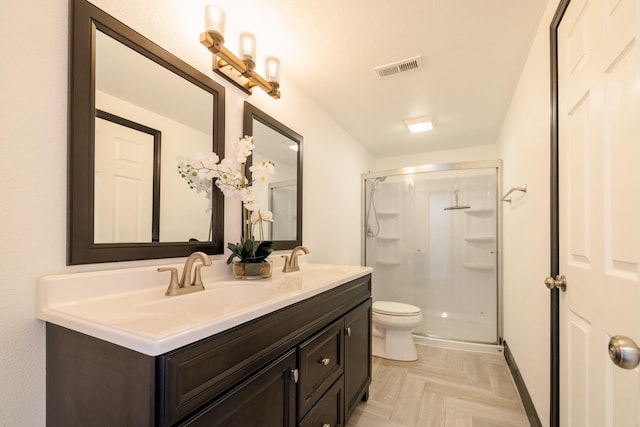 full bath featuring a shower stall, double vanity, and toilet