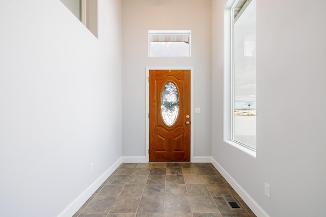 entrance foyer with plenty of natural light, baseboards, and dark stone finish floors