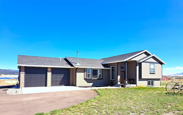 view of front of property with an attached garage, asphalt driveway, a front lawn, a mountain view, and a shingled roof