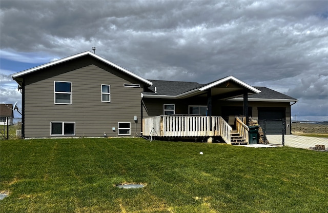 rear view of house with a garage, driveway, a deck, and roof with shingles