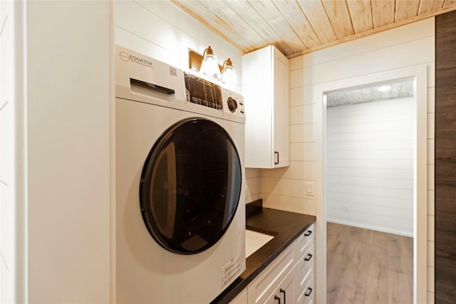 laundry room with wood ceiling, wood finished floors, cabinet space, and washer / dryer
