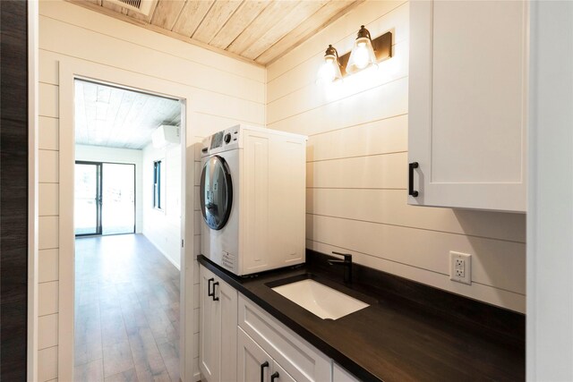interior space with stacked washer / drying machine, wood walls, wood finished floors, wooden ceiling, and a sink