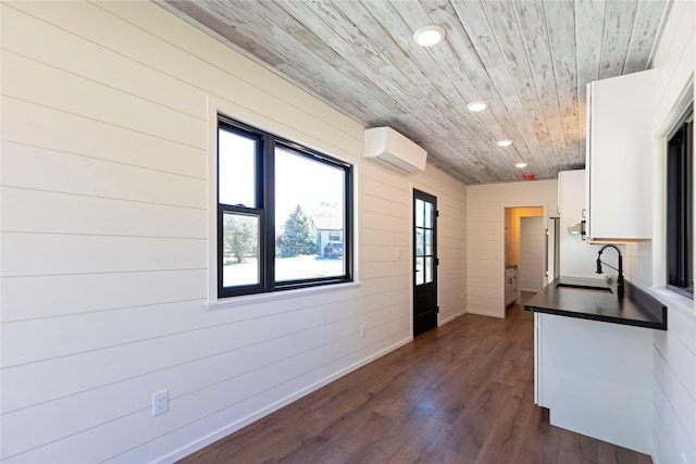 kitchen with a wall unit AC, dark countertops, recessed lighting, white cabinetry, and wooden ceiling