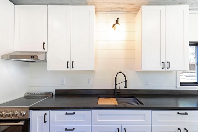 kitchen featuring white cabinets, a sink, electric range, dark countertops, and under cabinet range hood