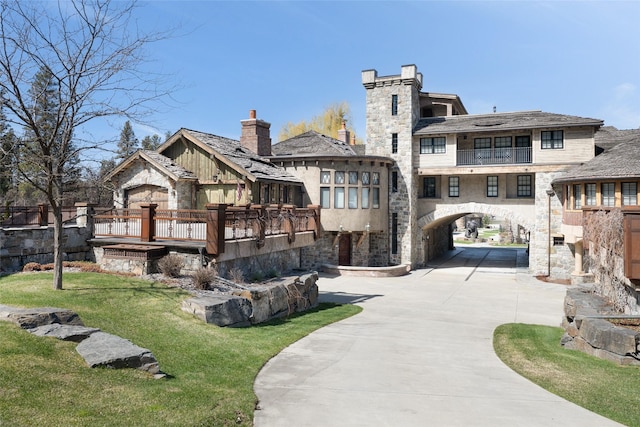 30 Bear Dance Vlg, Bigfork, MT 59911 - rear view of property with concrete driveway, a carport, stone siding, a yard, and a balcony