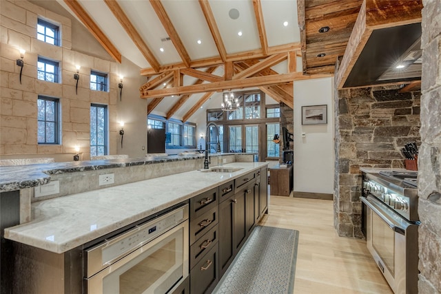 30 Bear Dance Vlg, Bigfork, MT 59911 - kitchen with appliances with stainless steel finishes, wall chimney range hood, high vaulted ceiling, light wood-type flooring, and beamed ceiling