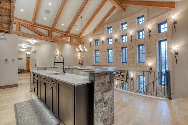 30 Bear Dance Vlg, Bigfork, MT 59911 - kitchen with high vaulted ceiling, light wood-style flooring, beam ceiling, a kitchen island with sink, and light stone countertops