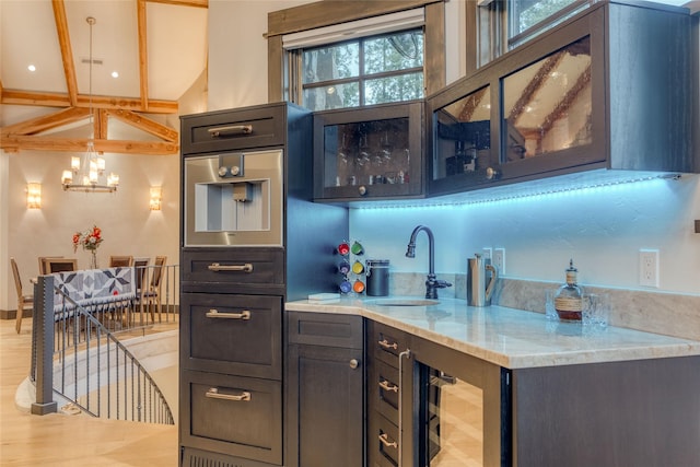 30 Bear Dance Vlg, Bigfork, MT 59911 - kitchen featuring a chandelier, beverage cooler, glass insert cabinets, light stone countertops, and hanging light fixtures