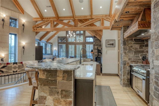 30 Bear Dance Vlg, Bigfork, MT 59911 - kitchen featuring double oven range, light wood finished floors, a center island with sink, high vaulted ceiling, and beamed ceiling
