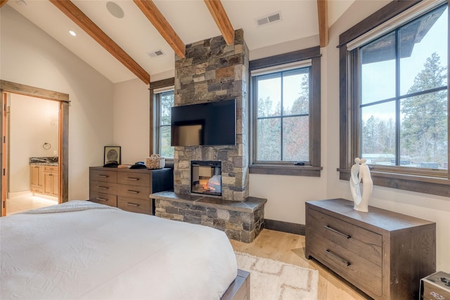 30 Bear Dance Vlg, Bigfork, MT 59911 - bedroom with light wood-type flooring, multiple windows, a fireplace, and connected bathroom
