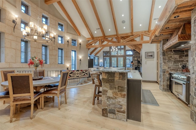 30 Bear Dance Vlg, Bigfork, MT 59911 - kitchen featuring high vaulted ceiling, high end stainless steel range, light wood-style flooring, beamed ceiling, and an island with sink