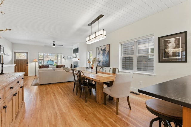 dining area with light wood finished floors, baseboards, a ceiling fan, and visible vents