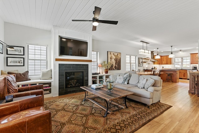 living area featuring wooden ceiling, a wealth of natural light, a ceiling fan, and light wood-style flooring