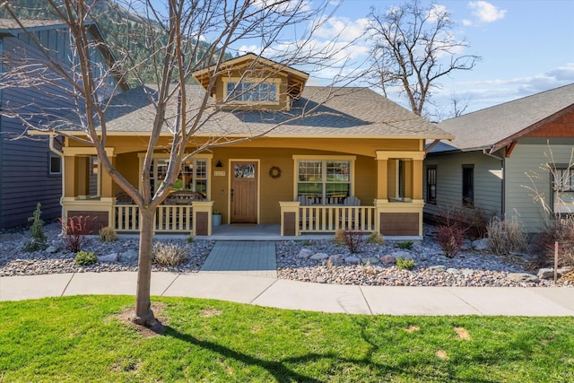 view of front of house featuring a porch, a shingled roof, and a front yard