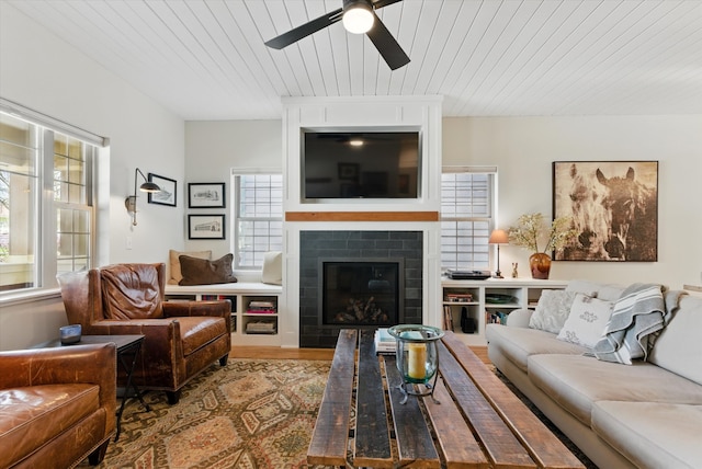 living area with wood finished floors, a wealth of natural light, wood ceiling, and ceiling fan