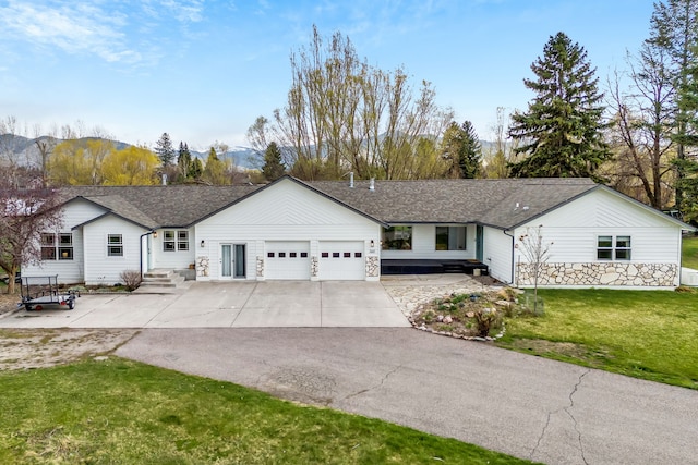ranch-style home featuring driveway, a front yard, a shingled roof, and a garage