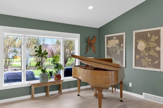 living area featuring vaulted ceiling, baseboards, wood finished floors, and visible vents