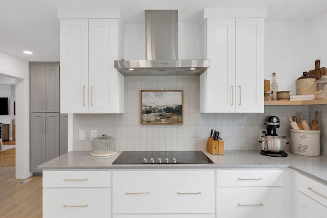 kitchen featuring recessed lighting, light wood-type flooring, wall chimney exhaust hood, black electric stovetop, and white cabinetry