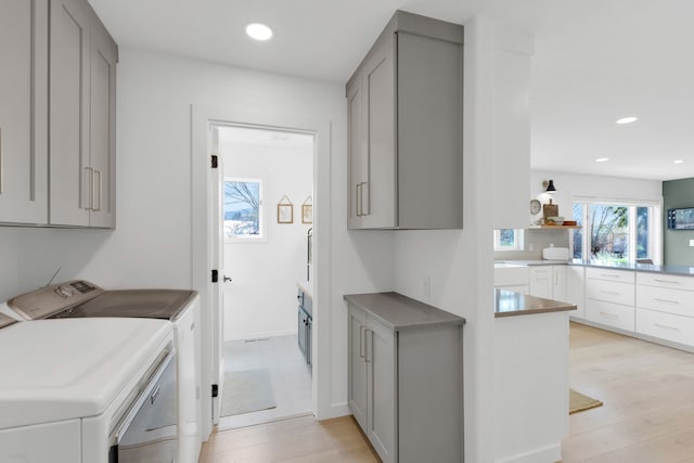 laundry room with cabinet space, light wood-style floors, recessed lighting, and separate washer and dryer