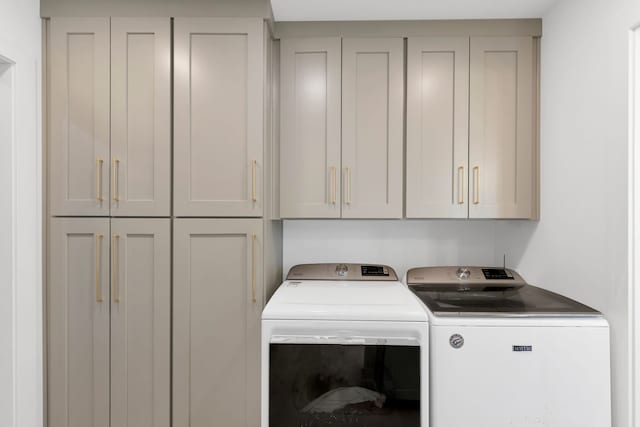 clothes washing area featuring washing machine and dryer and cabinet space
