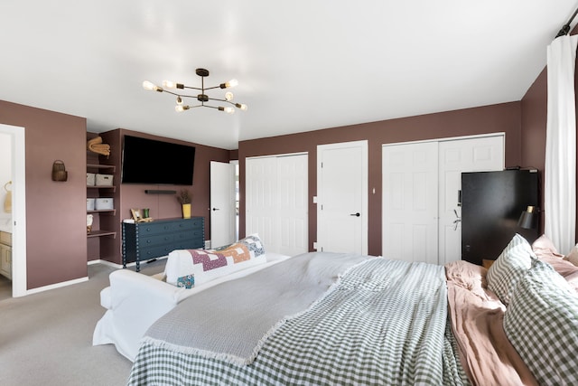 bedroom featuring a chandelier, two closets, carpet floors, baseboards, and freestanding refrigerator