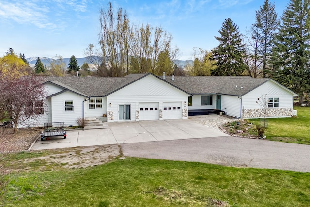 ranch-style house featuring a front lawn, a mountain view, driveway, and a garage
