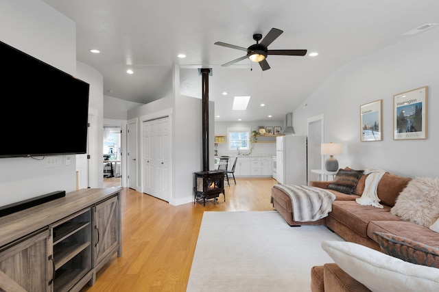 living room with recessed lighting, vaulted ceiling with skylight, light wood-style floors, and ceiling fan