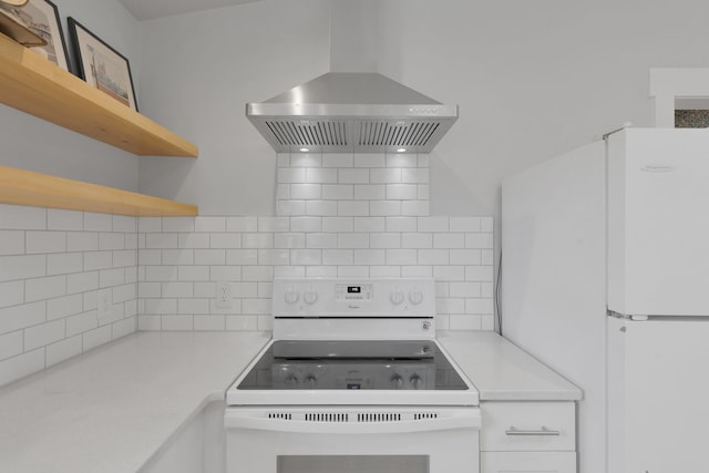 kitchen featuring open shelves, light countertops, wall chimney exhaust hood, and white appliances