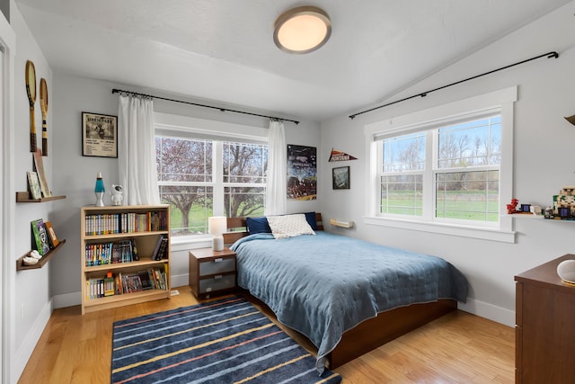 bedroom featuring baseboards, vaulted ceiling, and wood finished floors