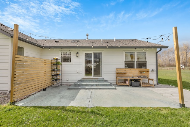 rear view of property featuring fence, a yard, a patio, entry steps, and roof with shingles