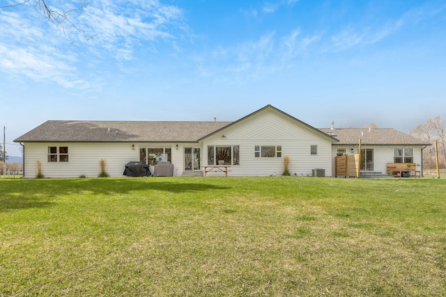 rear view of house with roof with shingles and a yard