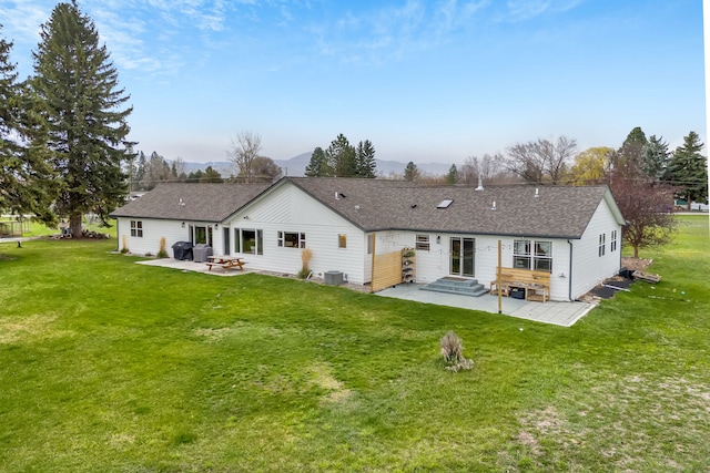 back of property featuring entry steps, a lawn, a patio, and a mountain view