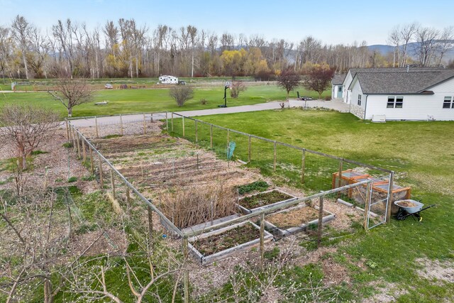 view of yard with fence, a rural view, and a garden