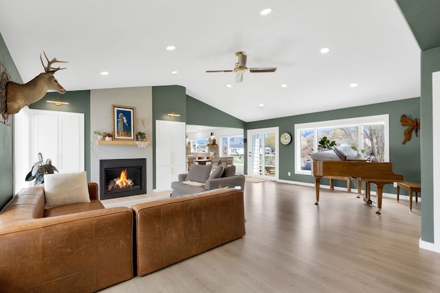 living room with baseboards, lofted ceiling, a ceiling fan, wood finished floors, and a large fireplace