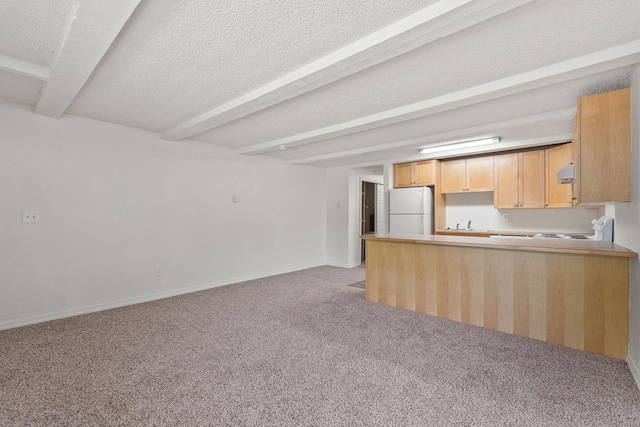 121 Iowa Ave Unit 1G, Whitefish, MT 59937 - kitchen featuring freestanding refrigerator, beam ceiling, light carpet, open floor plan, and a peninsula
