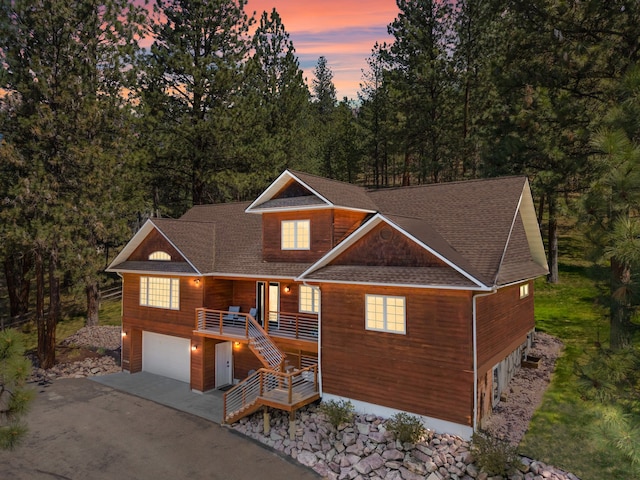 chalet / cabin featuring driveway, roof with shingles, stairs, and a garage