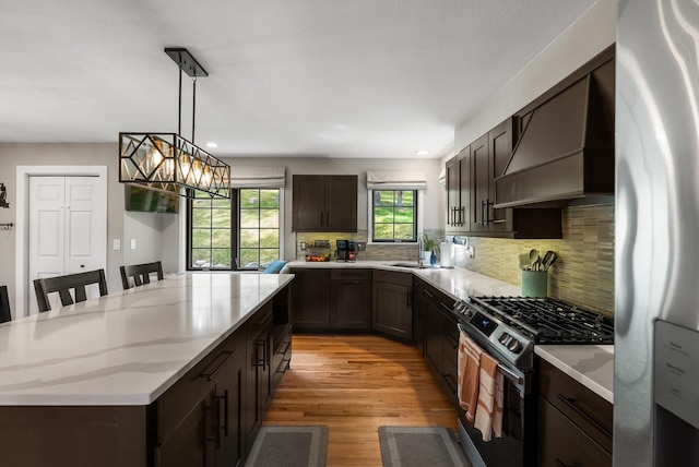 kitchen featuring a sink, dark brown cabinetry, light wood-style flooring, appliances with stainless steel finishes, and a kitchen island