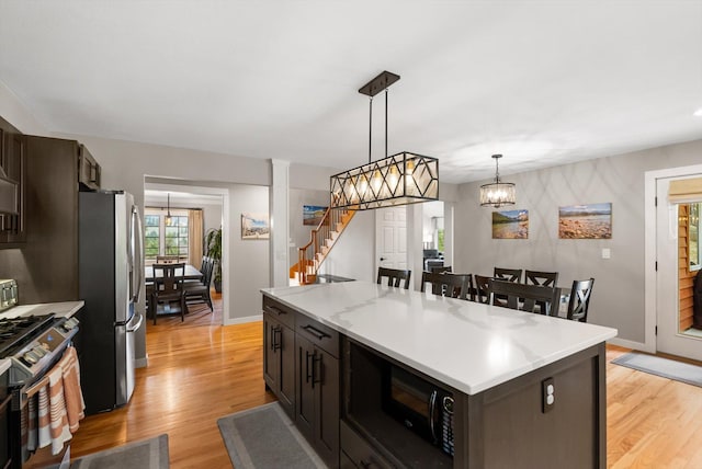 kitchen with light wood-type flooring, a center island, pendant lighting, and stainless steel appliances