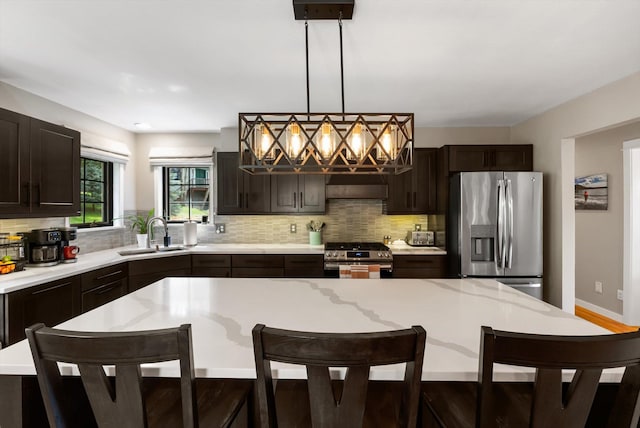 kitchen featuring backsplash, appliances with stainless steel finishes, a breakfast bar, and a sink