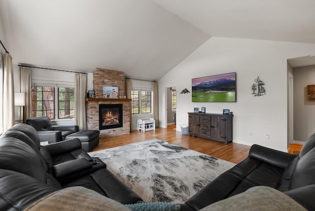 living room featuring baseboards, vaulted ceiling, wood finished floors, and a fireplace