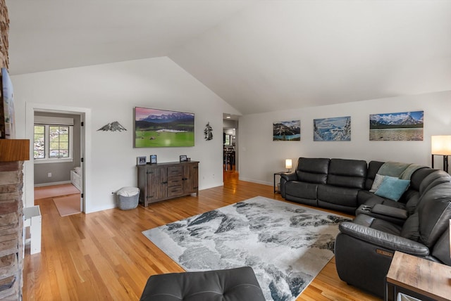 living room featuring high vaulted ceiling, baseboards, and light wood-style floors