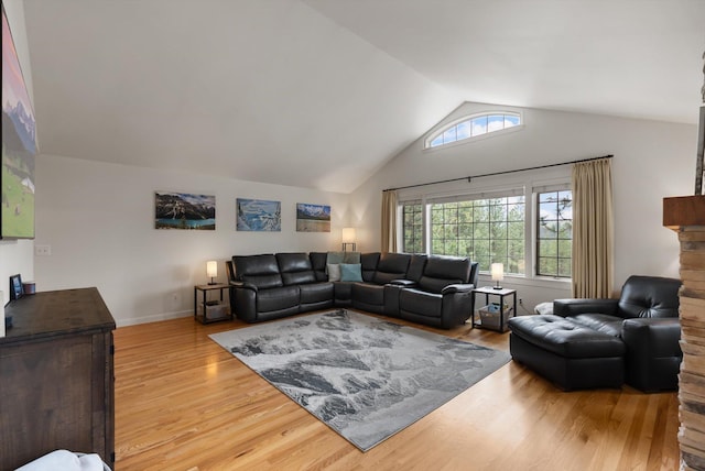 living room with baseboards, wood finished floors, and high vaulted ceiling