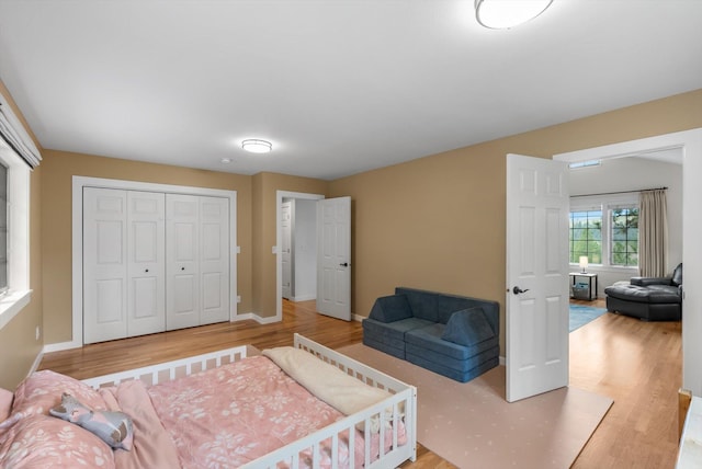 bedroom with baseboards, wood finished floors, and a closet