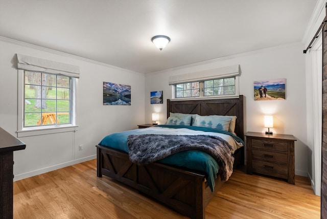 bedroom featuring baseboards, crown molding, and light wood finished floors